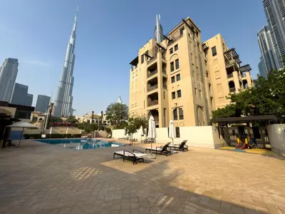 a building with benches and a pool in a city at Werova - Spacious 1-Bedroom Apartment for Rent in Dubai