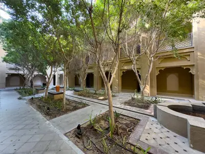 a courtyard of a building with trees and benches at Werova - Spacious 1-Bedroom Apartment for Rent in Dubai