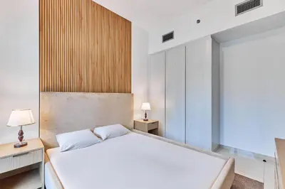 a bedroom with a white bed and a wooden wall at Compact 1 BHK Apartment in Dubai