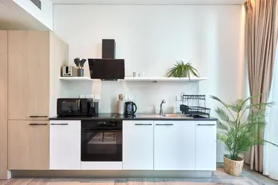 a kitchen with white cabinets and a sink at Stylish Studio in the Heart of DIFC in Dubai
