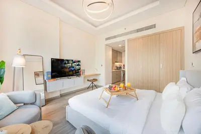 a white living room with a white couch and a table at Livin' Holidays -Studio - Azizi Magnificent Studio in Dubai
