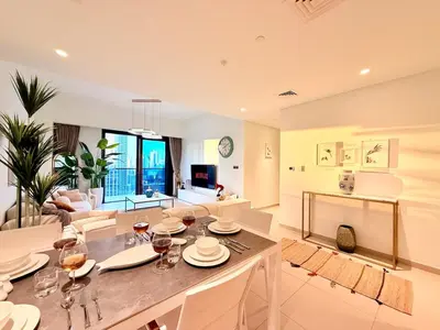 a dining room and living room with a table and chairs at SKYLiNE - 4 BR - BURJ KHALiFA & FOUNTAiN ViEW in Dubai