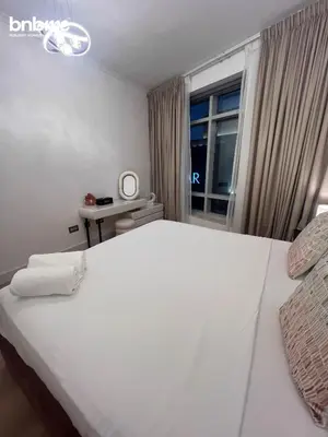 a white bed in a room with a window at bnbmehomes - Burj Views East Tower in Dubai