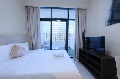 a bedroom with a white bed and a television at Premium Studio near Meydan Azizi Riviera 46 in Dubai