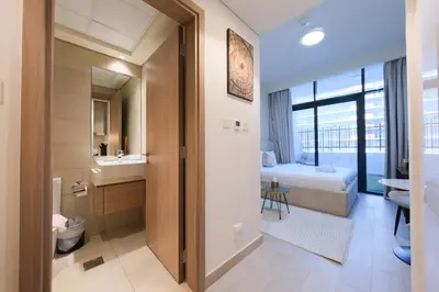 a bathroom with a toilet and a sink and a bed at Premium Studio near Meydan Azizi Riviera 46 in Dubai