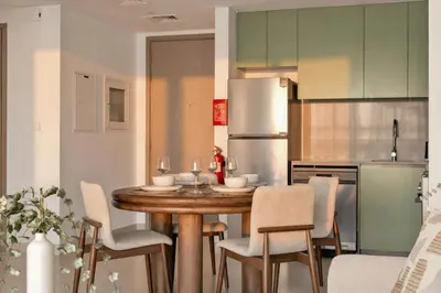 a kitchen with a table and chairs and a refrigerator at 1 Bedroom Apartment in Central Park, City Walk in Dubai