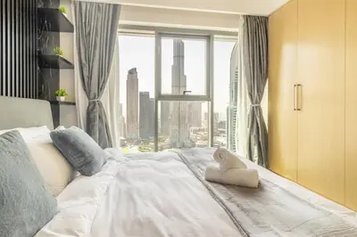 a bedroom with a white bed with a large window at Elite Burj Khalifa Fountain 4 BR Flat in Dubai