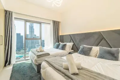 a hotel room with two beds and a large window at Elite Burj Khalifa Fountain 4 BR Flat in Dubai