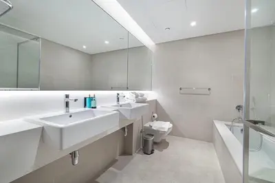 a bathroom with two sinks and a toilet and a mirror at Serene Waterfront Gem UPSCALE in Dubai