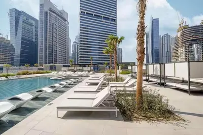 a row of benches next to a pool in a city at Stunning Studio With Burj Khalifa & Canal Views in Dubai