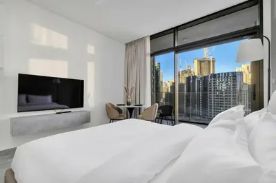 a white bedroom with a large bed and a large window at Stunning Studio With Burj Khalifa & Canal Views in Dubai
