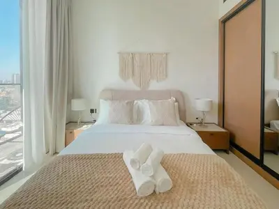 a bedroom with a bed with white towels on it at Warm Minimal 1BR in Binghatti Tulip with Free Parking! in Dubai