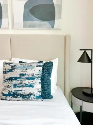 a bed with a blue and white pillow and a table at Binghatti Azure Ethereal Studio Haven with Pool & Gym! in Dubai