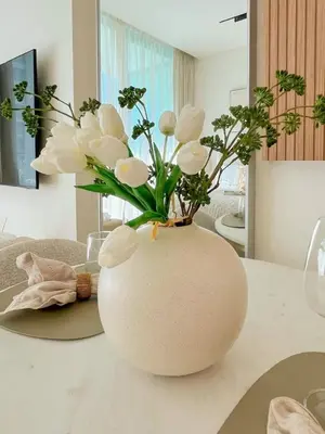 a vase filled with white flowers on a table at Warm-Toned Studio with City Views in Binghatti Azure in Dubai