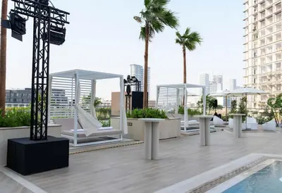 a rooftop patio with white chairs and a pool at Calm 1BR Haven with Private Pool in Binghatti Royale in Dubai