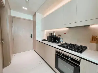 a kitchen with a stove top oven next to a refrigerator at Softline Studio with Open Views in Binghatti Phoenix! in Dubai