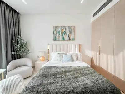 a bedroom with a large bed and a chair at Softline Studio with Open Views in Binghatti Phoenix! in Dubai