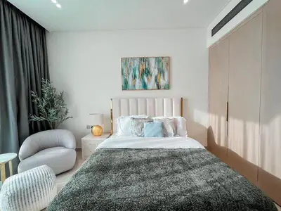 a bedroom with a large bed and a chair at Softline Studio with Open Views in Binghatti Phoenix! in Dubai