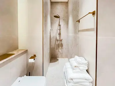 a bathroom with a toilet and a shower with towels at Binghatti Phantom's Elegant 1BR with Private Pool! in Dubai