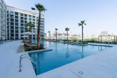a large swimming pool with palm trees and a building at Elevated Studio Living at Binghatti Phoenix in Dubai