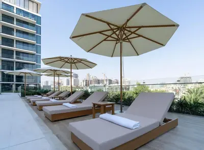 a row of lounge chairs and umbrellas on a roof at Elevated Studio Living at Binghatti Phoenix in Dubai