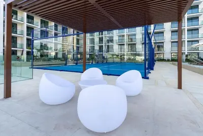 a group of white chairs in front of a building at Elevated Studio Living at Binghatti Phoenix in Dubai