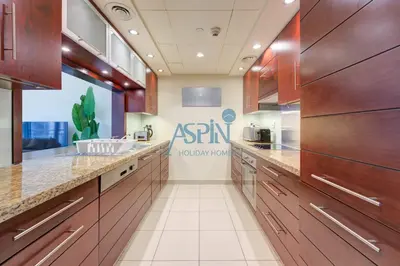 a kitchen with wooden cabinets and a sink at Aspin Brand New Premium Studio with Pool View - Burj Views in Dubai