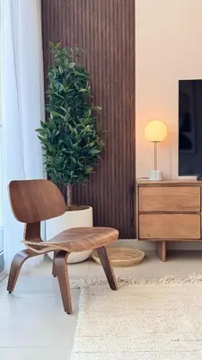 a wooden chair in a living room with a potted plant at 2 Bed with Direct Park Access - Calm and Peaceful in Dubai