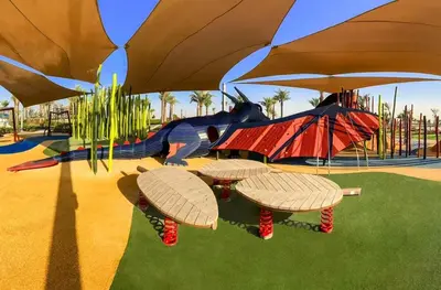 a playground with three picnic tables and a play structure at 2 Bed with Direct Park Access - Calm and Peaceful in Dubai