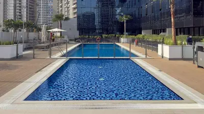 a large pool with blue water in a city at Modern 1BR Apartment w Balcony in Meydan in Dubai