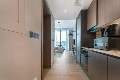 a kitchen with a long hallway leading to a living room at Oxford Gardens Premium Studio with Cinema & Game Room in Dubai