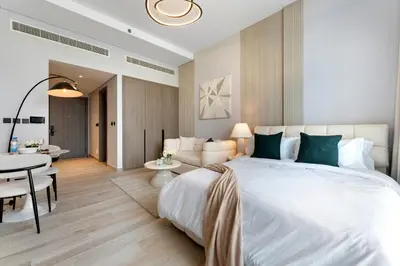 a bedroom with a large white bed and a dining room at Oxford Gardens Premium Studio with Cinema & Game Room in Dubai
