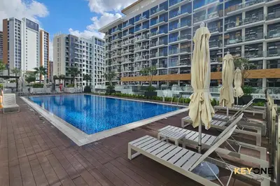 a swimming pool with chairs and umbrellas next to a building at Stylish Riviera Studio Near Downtown in Dubai