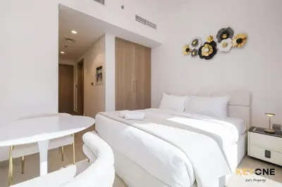 a white bedroom with a bed and a table at Stylish Riviera Studio Near Downtown in Dubai
