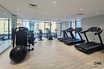 a gym with several treadmills and elliptical machines at Stylish Riviera Studio Near Downtown in Dubai