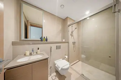 a bathroom with a toilet and a sink and a shower at VayK - Stylish 2BR & Maids Apartment in Sobha Hartland in Dubai