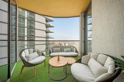 a room with two chairs and a table on a balcony at VayK - Stylish 2BR & Maids Apartment in Sobha Hartland in Dubai