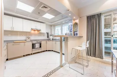 a kitchen with white cabinets and a table and chairs at Minutes from Marina Promenade, Surrounded by Shops, and a Short Drive to Ain Dubai, Opal Tower, Dubai Marina by Deluxe Holiday Homes in Dubai