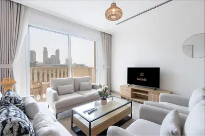 a living room with white furniture and a large window at Relaxing 1BR Peaceful Family Living in JVC in Dubai