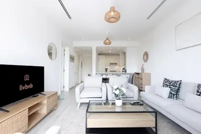 a living room with white furniture and a flat screen tv at Relaxing 1BR Peaceful Family Living in JVC in Dubai