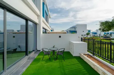 a patio with a table and chairs on a balcony at Stylish 4 Bedroom Home with Garden in DAMAC Lagoons in Dubai Marina