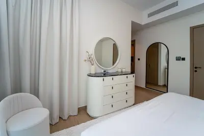 a white bedroom with a white dresser and a mirror at Stylish 4 Bedroom Home with Garden in DAMAC Lagoons in Dubai Marina