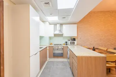 a kitchen with white cabinets and a kitchen island at Premium 1BR King Bed Dubai Healthcare City in Dubai