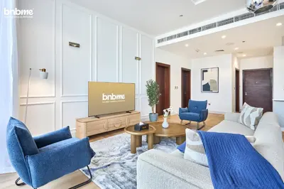 a living room with blue chairs and a tv at bnbmehomes - Tiara Residence in Dubai