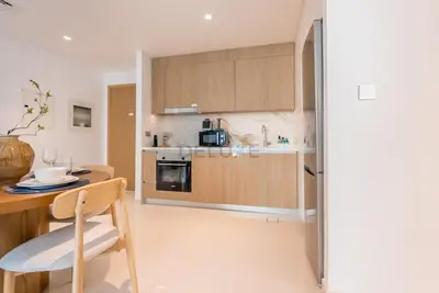 a kitchen with wooden cabinets and a table with a chair at Prime Waterfront Location with Stunning Palm Jumeirah Views, Close to Dubai Top Attractions - Beach Vista Tower 2, Emaar Beachfront by Deluxe Holiday Homes in Dubai