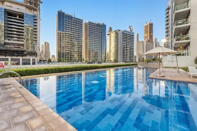 a swimming pool with a city skyline in the background at Chic 1BR at Reva Stunning Canal Views in Dubai