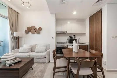 a kitchen and living room with a table and a couch at Chic 1BR at Reva Stunning Canal Views in Dubai