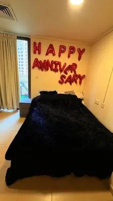 a bedroom with a black bed with a happy anniversary sign at 1 Bhk with open terrace in Dubai