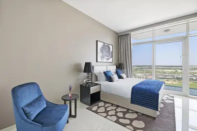 a bedroom with a bed and a chair and a window at VayK - Chic Hotel Style Studio in Damac Hills in Dubai