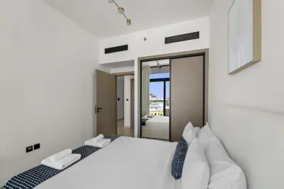 a bedroom with a bed with white sheets and pillows at VayK - Amazing 1BR in Jvc in Dubai